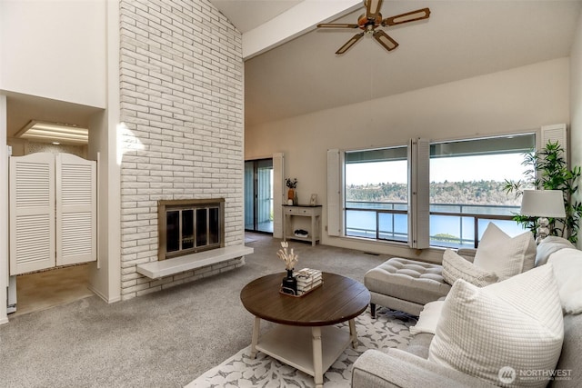carpeted living room featuring a water view, high vaulted ceiling, a fireplace, ceiling fan, and beam ceiling
