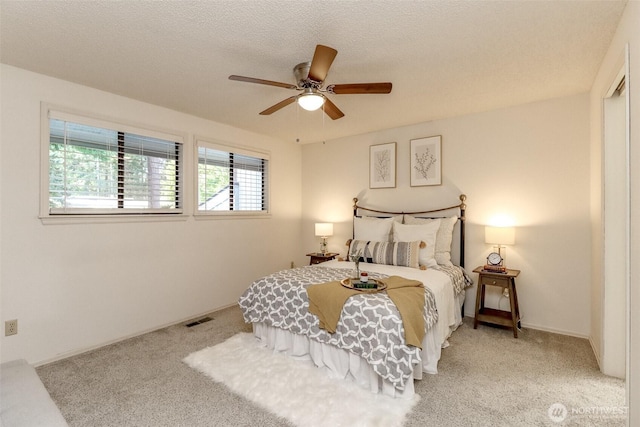 bedroom with ceiling fan, carpet, a textured ceiling, and visible vents