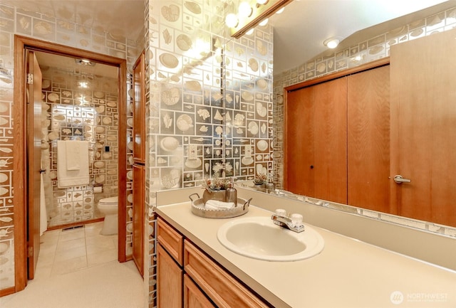 bathroom with visible vents, wallpapered walls, tile patterned floors, toilet, and vanity