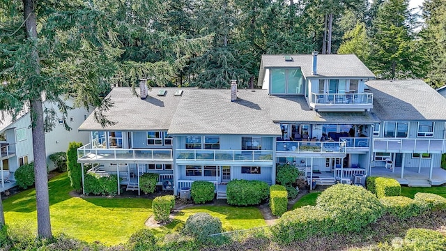 rear view of house with a balcony and a yard
