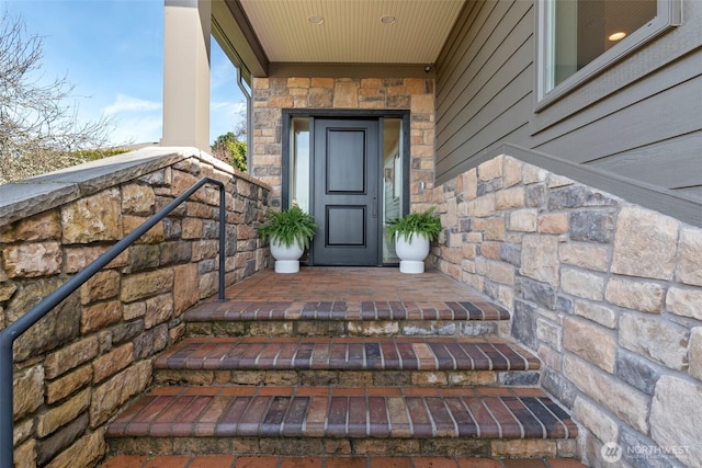 entrance to property featuring a porch and stone siding
