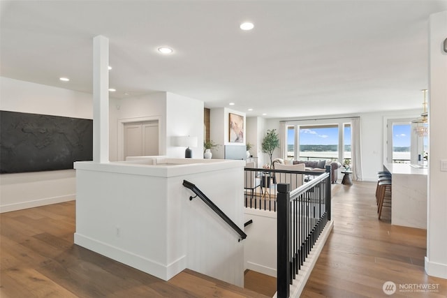 stairway featuring baseboards, wood finished floors, and recessed lighting