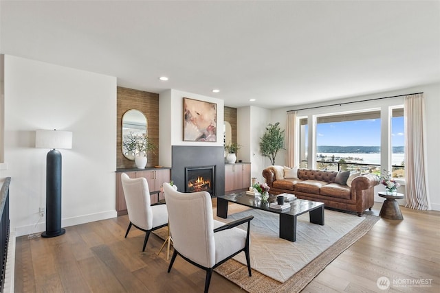 living room with a glass covered fireplace, baseboards, light wood finished floors, and recessed lighting