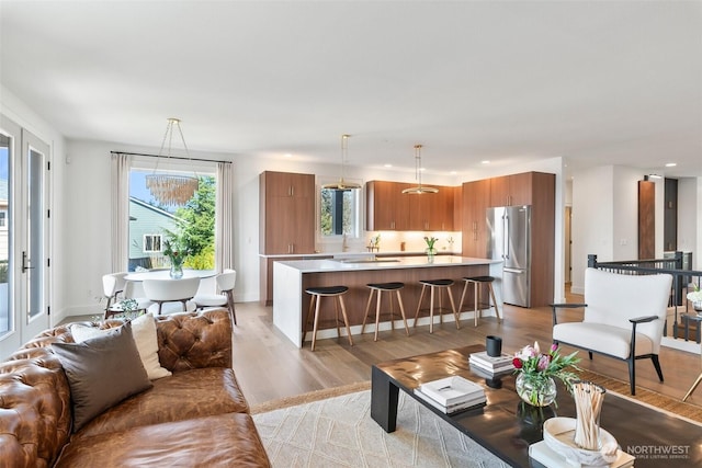 living room with recessed lighting, baseboards, and light wood-type flooring