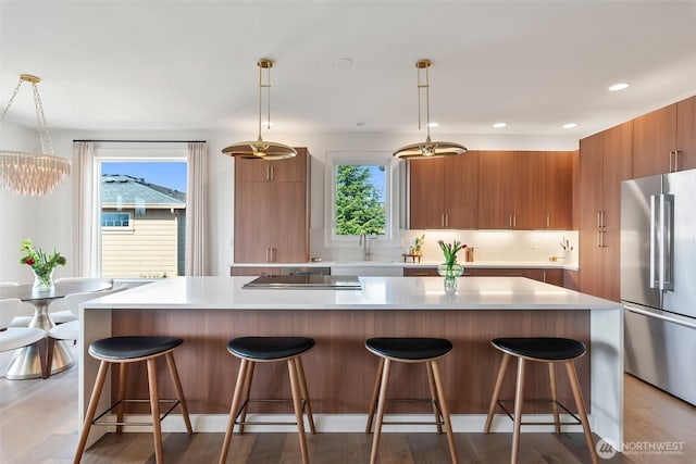 kitchen featuring modern cabinets, a healthy amount of sunlight, high quality fridge, and brown cabinetry