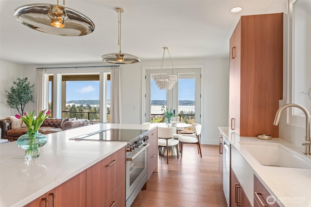 kitchen with a wealth of natural light, a sink, brown cabinets, and appliances with stainless steel finishes