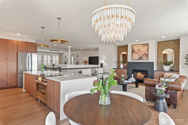 dining space featuring light wood finished floors, recessed lighting, and a glass covered fireplace