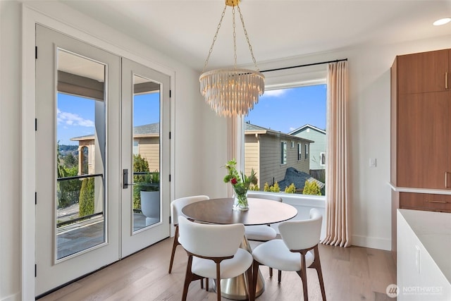 dining room with baseboards, light wood-style flooring, french doors, and a notable chandelier