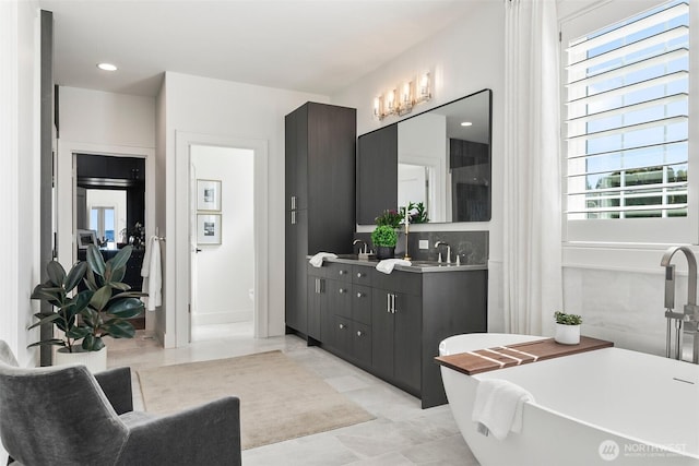 bathroom with a sink, a soaking tub, and plenty of natural light