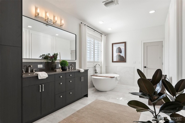 bathroom featuring a sink, a freestanding bath, visible vents, and double vanity