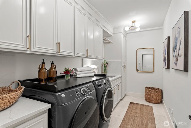 clothes washing area featuring baseboards, washing machine and dryer, cabinet space, and a sink