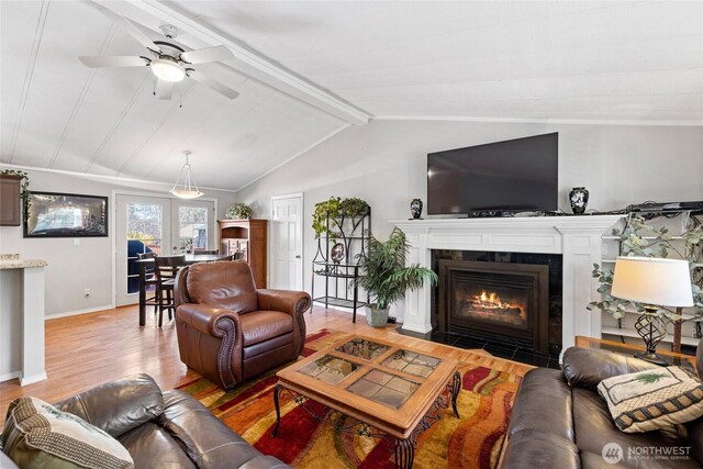 living area featuring a ceiling fan, lofted ceiling with beams, a fireplace, wood finished floors, and baseboards
