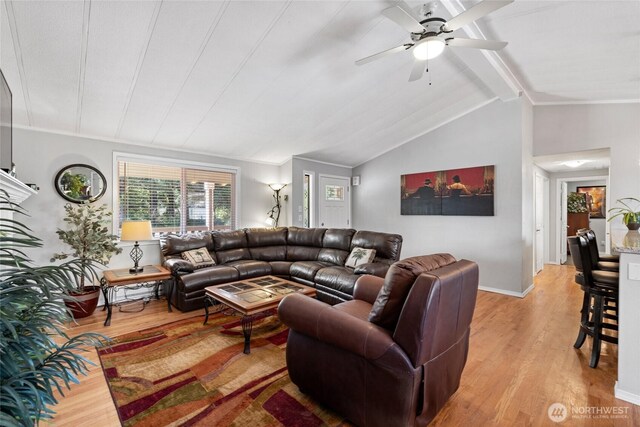 living area with vaulted ceiling with beams, light wood-style floors, baseboards, and a ceiling fan