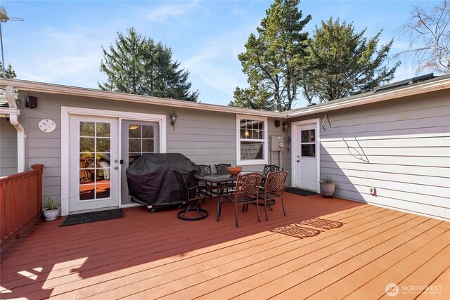 wooden deck with outdoor dining area and area for grilling