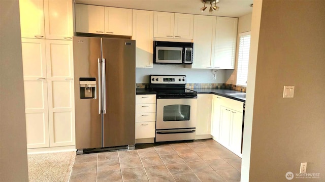 485 SW Bayshore Dr Unit C301, Oak Harbor, WA 98277 - kitchen featuring light tile patterned floors, white cabinets, a sink, dark countertops, and stainless steel appliances