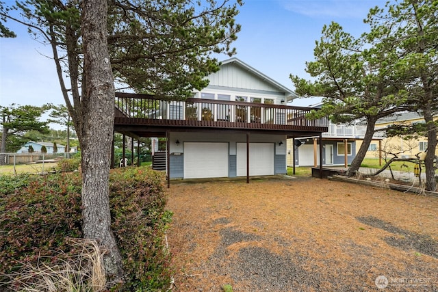 rear view of house featuring driveway, an attached garage, stairway, and a deck