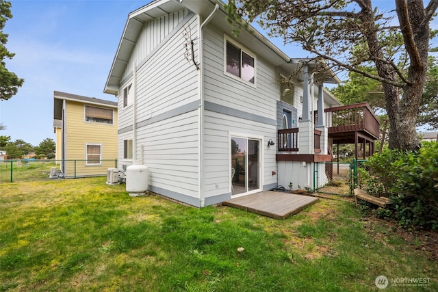 back of property with a fenced backyard, a lawn, a wooden deck, and central AC