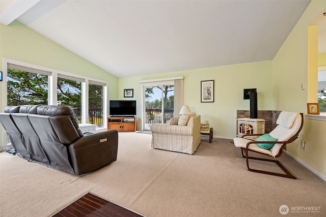 living area with baseboards, vaulted ceiling, a wood stove, and carpet