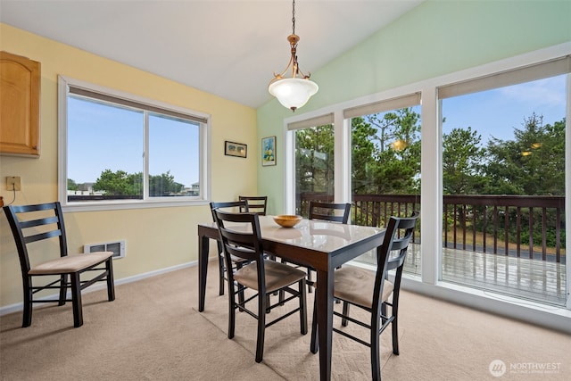 dining space with light colored carpet, lofted ceiling, and baseboards