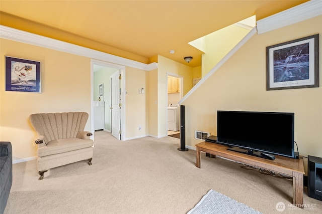living area featuring baseboards, washing machine and clothes dryer, and carpet flooring