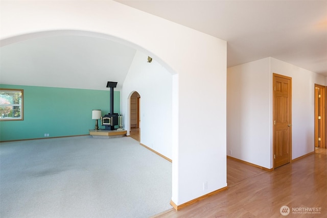 305 W Eunice St, Sequim, WA 98382 - additional living space with lofted ceiling, baseboards, a wood stove, and arched walkways
