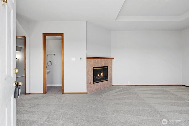 unfurnished living room featuring a tile fireplace, baseboards, and carpet