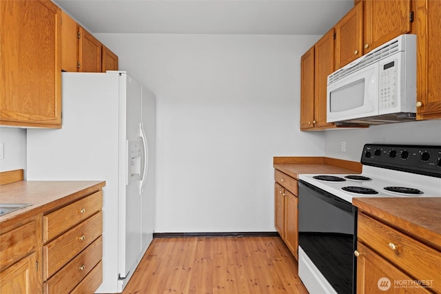 kitchen featuring brown cabinetry, light countertops, white appliances, and light wood-type flooring