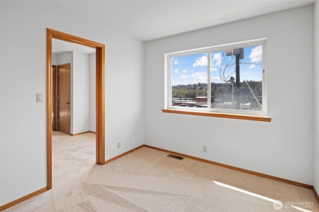 unfurnished room with carpet floors, visible vents, and baseboards