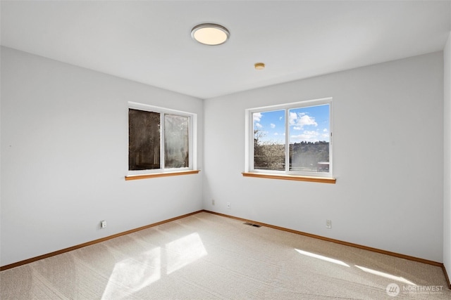 empty room featuring baseboards, visible vents, and light colored carpet