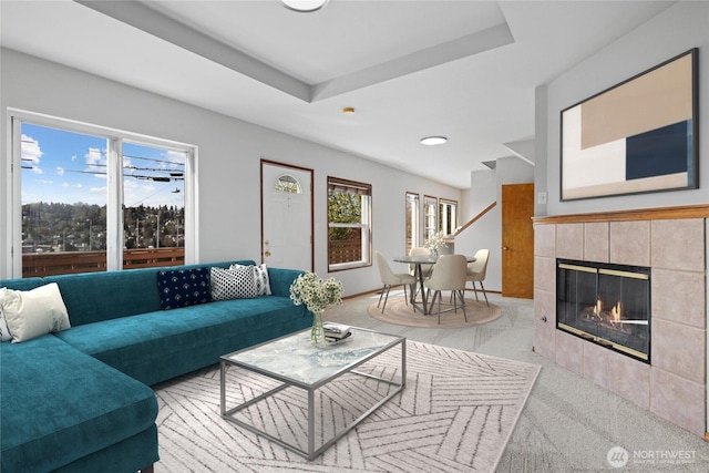living room featuring baseboards, a wealth of natural light, and a tiled fireplace