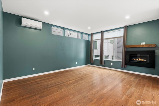 2620 SW Nevada St, Seattle, WA 98126 - unfurnished living room with a glass covered fireplace, recessed lighting, wood finished floors, a wall mounted air conditioner, and baseboards