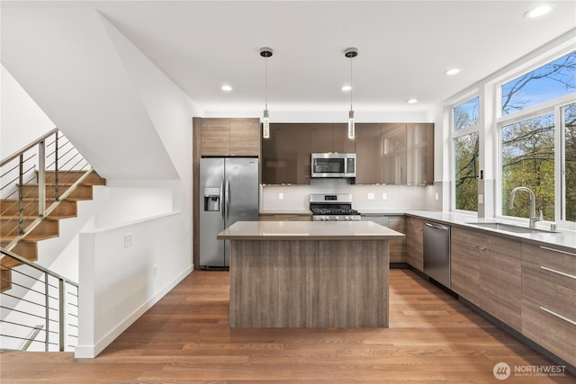 2620 SW Nevada St, Seattle, WA 98126 - kitchen featuring modern cabinets, a sink, appliances with stainless steel finishes, light wood-style floors, and a kitchen island