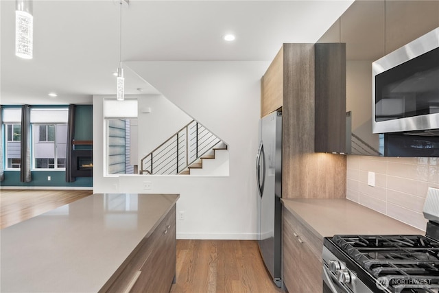 2620 SW Nevada St, Seattle, WA 98126 - kitchen featuring a warm lit fireplace, recessed lighting, modern cabinets, stainless steel appliances, and light wood finished floors