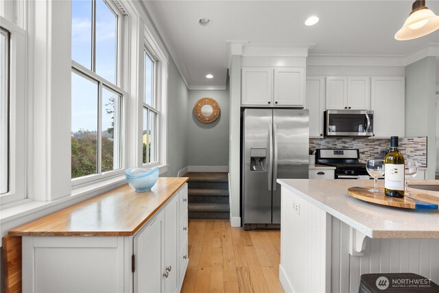 78 Pacifica Ln, Pacific Beach, WA 98571 - kitchen with light wood finished floors, ornamental molding, stainless steel appliances, tasteful backsplash, and white cabinetry