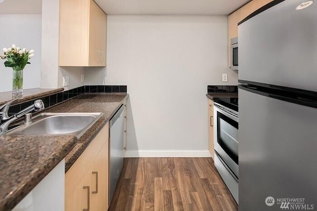 108 5th Ave S Unit 520, Seattle, WA 98104 - kitchen featuring dark wood-type flooring, baseboards, a sink, dark countertops, and appliances with stainless steel finishes