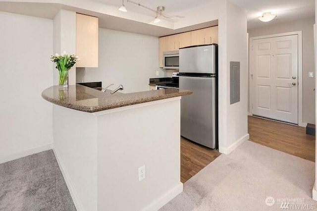 108 5th Ave S Unit 520, Seattle, WA 98104 - kitchen with baseboards, dark stone countertops, a peninsula, and appliances with stainless steel finishes