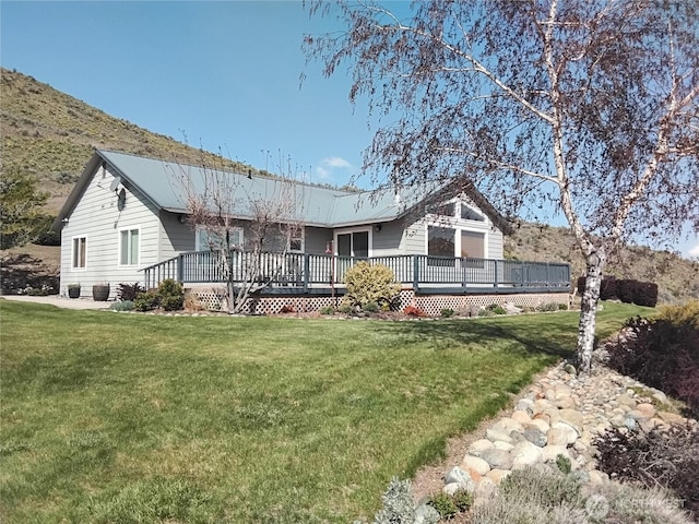 ranch-style home featuring a wooden deck, a front lawn, and metal roof