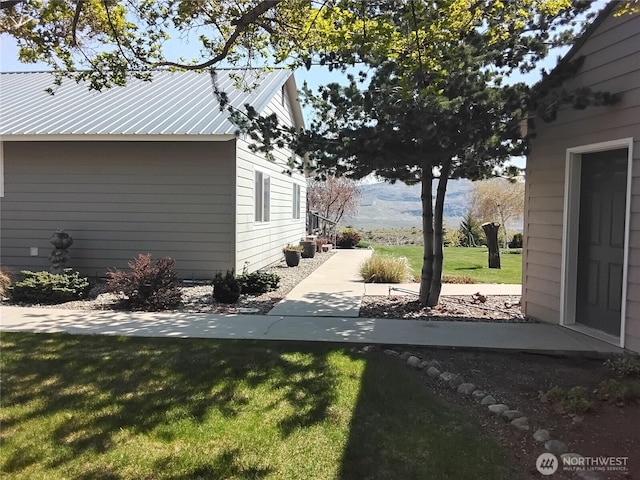 view of side of home featuring a lawn and metal roof