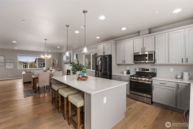kitchen featuring an inviting chandelier, light countertops, a center island, backsplash, and stainless steel appliances