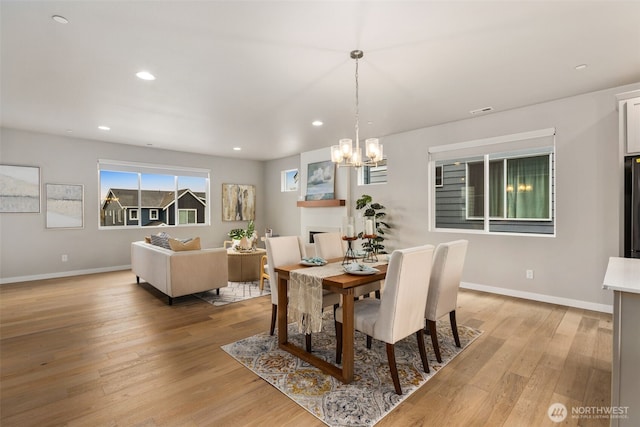 dining space with light wood-style flooring, visible vents, recessed lighting, a notable chandelier, and baseboards