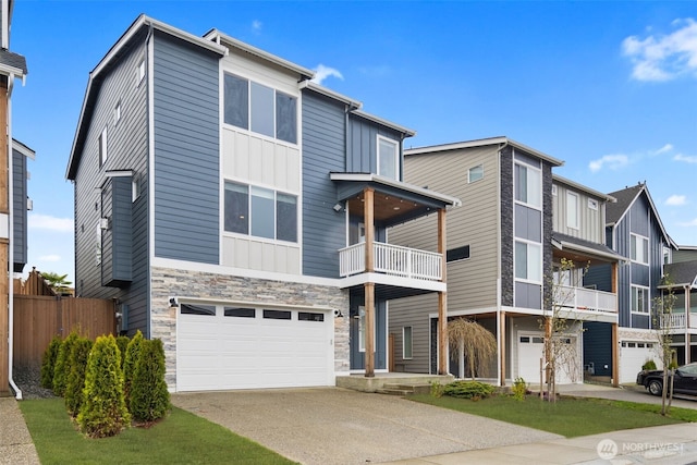 view of front of property with a balcony, an attached garage, board and batten siding, driveway, and stone siding