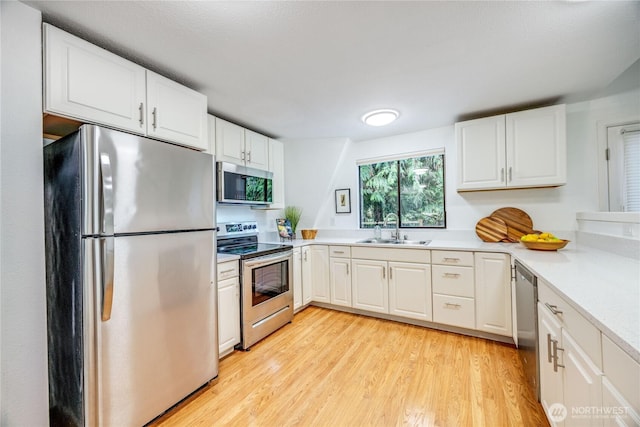 6455 NE Brigham Rd, Bainbridge Island, WA 98110 - kitchen with stainless steel appliances, a sink, white cabinets, light wood-style flooring, and light countertops