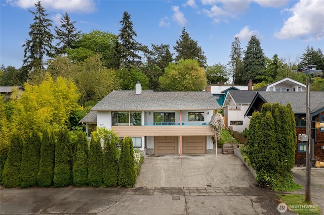 5510 3rd Ave NW, Seattle, WA 98107 - view of front of house with driveway, a garage, stucco siding, a chimney, and a balcony