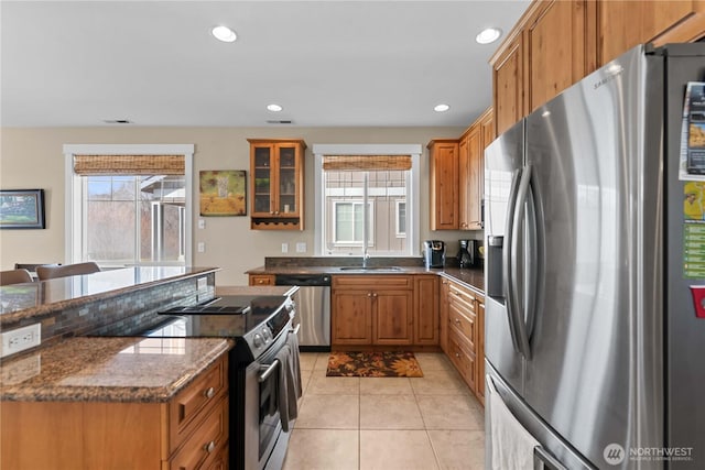 kitchen with light tile patterned flooring, appliances with stainless steel finishes, brown cabinetry, and recessed lighting