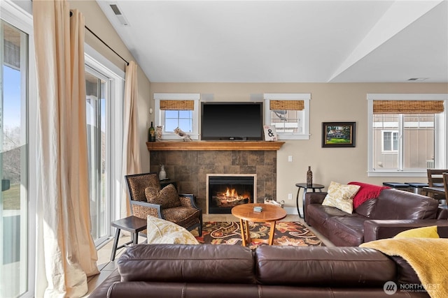 living area with a fireplace, visible vents, and vaulted ceiling