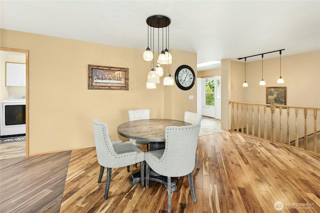 dining space with wood finished floors, rail lighting, and washer / dryer