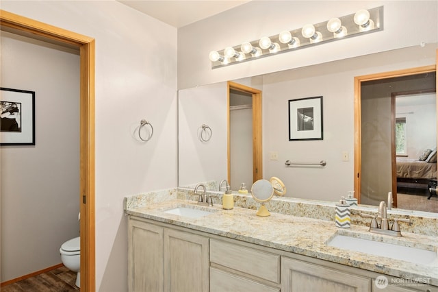 ensuite bathroom with ensuite bathroom, double vanity, a sink, and toilet