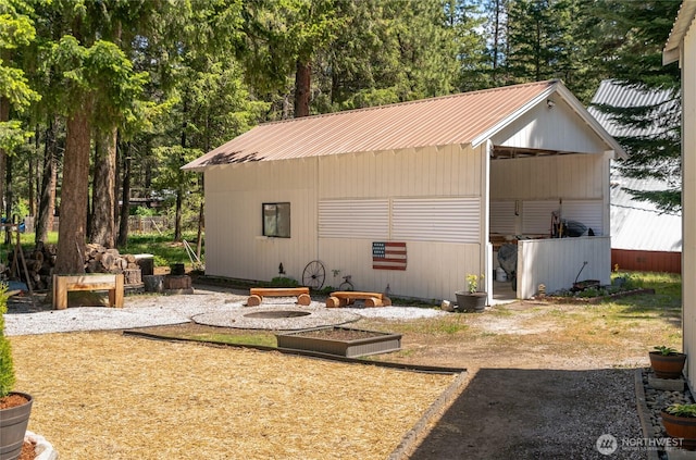 24502 Saddle St, Leavenworth, WA 98826 - back of property with a pole building, metal roof, an outbuilding, a vegetable garden, and view of wooded area
