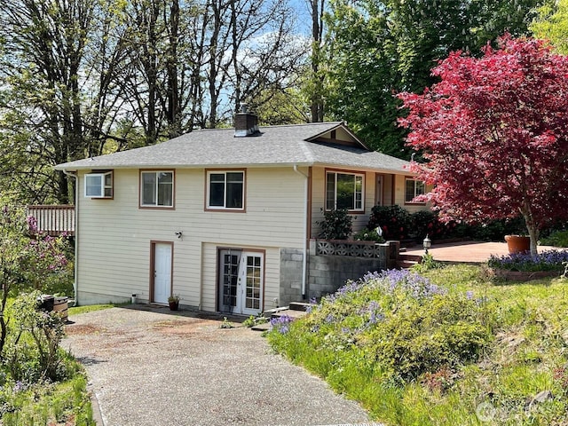 exterior space with roof with shingles, a chimney, french doors, and a wooden deck