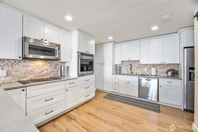 kitchen featuring white cabinetry, a sink, appliances with stainless steel finishes, and light wood-style floors